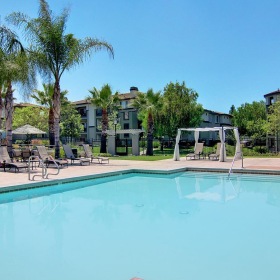 a swimming pool with chairs and umbrellas by it